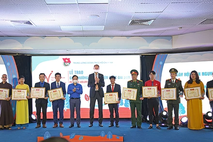 Đồng chí Nguyễn Anh Tuấn và ông Patrick Haverman, Phó Trưởng Đại diện Liên hợp quốc tại Việt Nam (thứ 5 và 6 từ trái sang trong ảnh) trao Giải thưởng Tình nguyện quốc gia năm 2021 tặng các câu lạc bộ, đội, nhóm tình nguyện tiêu biểu.