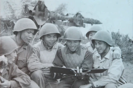 Ông Nguyễn Quang Hùng (ngồi giữa, tay cầm sổ rút kinh nghiệm chiến đấu) khi còn là sĩ quan điều khiển cùng với kíp chiến đấu Tiểu đoàn 62 tại trận địa Cổ Nhuế, Hà Nội, năm 1967. (Ảnh: nhân vật cung cấp)