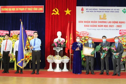 Thừa uỷ quyền, Phó Chủ tịch Uỷ ban nhân dân tỉnh Vĩnh Long Nguyễn Thị Quyên Thanh trao Huân chương Lao động hạng Nhì cho nhà trường vào sáng 23/12. (Ảnh: BÁ DŨNG)