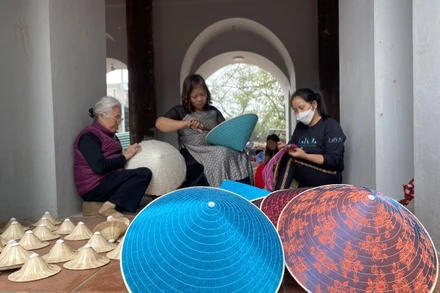 Các nghệ nhân làng Chuông gia công nón cho các diễn viên múa. (Ảnh: MINH NGHĨA)