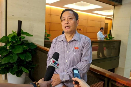 Đại biểu Hà Quốc Trị trao đổi bên hành lang Quốc hội. (Ảnh: TRUNG HƯNG)