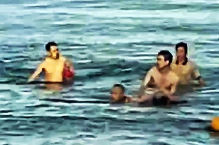 Hình ảnh Trung tá Bùi Văn Nhiên cùng người dân cứu cháu bé bị đuối nước. (Ảnh: qdnd.vn)