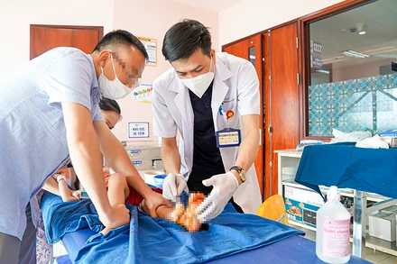 Bác sĩ xử trí vết thương cho bé bị tai nạn cửa trượt tự động. 