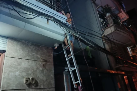 Lực lượng công an dùng thang đưa người mắc kẹt bên trong nhà thoát ra ngoài.