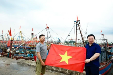 Ngư dân Nguyễn Văn Hà, trú tại đội 1, thị trấn Diêm Điền (huyện Thái Thụy, tỉnh Thái Bình) nhận cờ Tổ quốc tại cảng cá Diêm Điền.