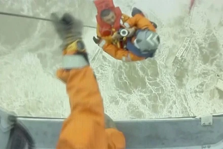 Nhân viên cứu nạn hỗ trợ thành viên thủy thủ đoàn lên trực thăng. (Ảnh: Reuters)