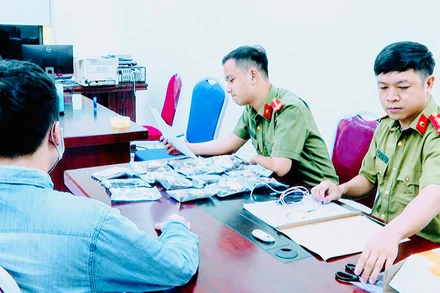 Công an làm việc với đối tượng có thiết bị công nghệ cao bị thu giữ. (Ảnh: Công an cung cấp) 