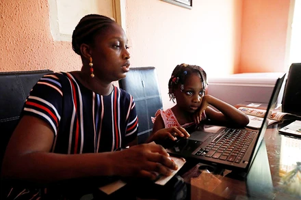 Một phụ nữ Nigeria đang cùng con học online. (Ảnh: Reuters)