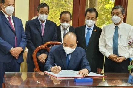 Chủ tịch nước Nguyễn Xuân Phúc viết cảm tưởng vào Sổ vàng tại Khu lưu niệm Chủ tịch Tôn Đức Thắng. (Ảnh: TTXVN)