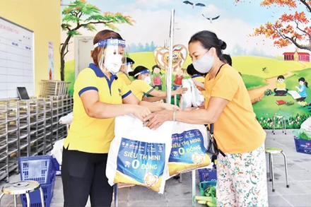 Nhân viên Công ty CP Vàng bạc đá quý Phú Nhuận (PNJ) hỗ trợ người dân tại “Siêu thị mini 0 đồng” trên địa bàn Hà Nội. Ảnh: Thủy Nguyên 