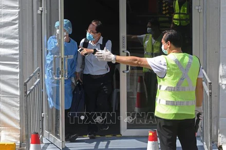 Nhân viên hướng dẫn hành khách trong chương trình Làn đi lại cho người đã tiêm vaccine (VTL), tại Singapore . (Ảnh: THX/TTXVN)