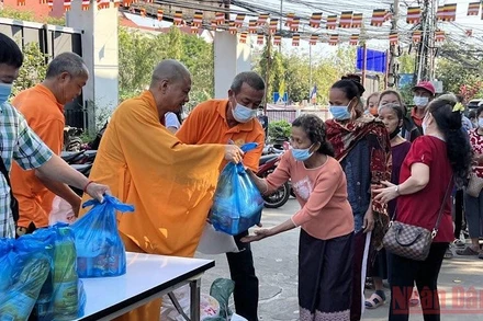 Thượng tọa Thích Minh Quang (thứ 3 từ trái qua) trao hỗ trợ kiều bào nghèo ở Thủ đô Vientiane trong lễ Thượng nguyên 2022. (ẢNH: XUÂN SƠN)