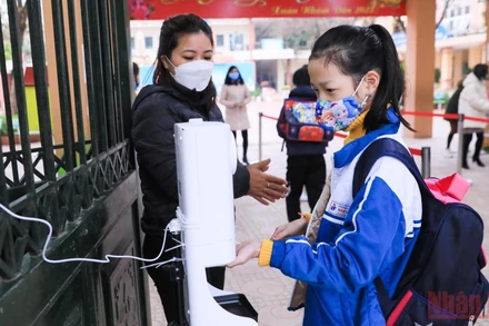 Các giáo viên trường tiểu học tại huyện Hoài Đức nhắc các em học sinh sát khuẩn tay, kiểm tra thân nhiệt trước khi vào học. (Ảnh: DUY LINH)