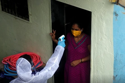 Nhân viên y tế đo thân nhiệt của người dân sống trong khu ổ chuột tại Mumbai, Ấn Độ, ngày 27-6. (Ảnh: Reuters)