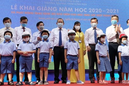 Phó Thủ tướng Trương Hòa Bình cùng các đại biểu trao tặng mũ bảo hiểm cho các em học sinh lớp Một tại trường Tiểu học Trần Hưng Đạo, quận 1, TP Hồ Chí Minh. (Ảnh: QUÝ HIỀN)