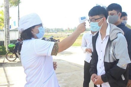 Thí sinh Trường THPT Hùng Vương (huyện Thăng Bình) được kiểm tra nhiệt độ khi đến làm thủ tục dự thi.