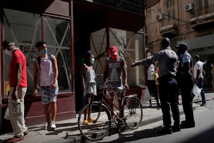 Cảnh sát hướng dẫn người dân tại Havana, Cuba, xếp hàng để mua thực phẩm. (Ảnh: Reuters)