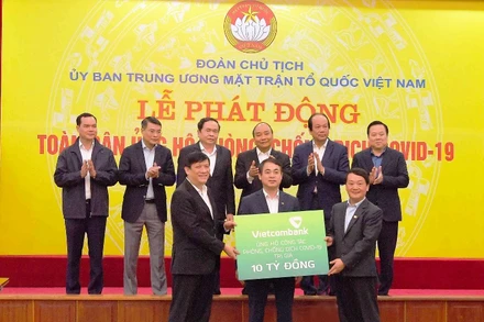Đồng chí Nghiêm Xuân Thành - Chủ tịch HĐQT Vietcombank (giữa) trao biển tượng trưng số tiền ủng hộ công tác phòng, chống dịch Covid-19 của Vietcombank tại Lễ phát động toàn dân ủng hộ phòng, chống dịch Covid-19 do Ủy ban Trung ương MTTQ Việt Nam phát động với sự chứng kiến của Thủ tướng Chính phủ và lãnh đạo các bộ, ban, ngành.
