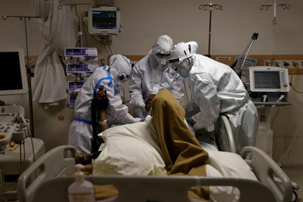 Các nhân viên y tế mặc đồ bảo hộ đang chăm sóc một bệnh nhân Covid-19 trong bệnh viện tại Ấn Độ. Ảnh: Reuters