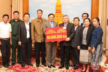 Đại sứ Việt Nam tại Lào Nguyễn Bá Hùng (thứ 5 từ trái qua) trao số tiền ủng hộ Lào, chiều 26-10.