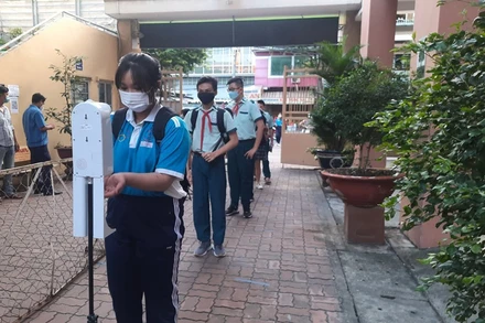 Học sinh tại Thành phố Hồ Chí Minh kiểm tra thân nhiệt, sát khuẩn tay trước khi vào lớp học.