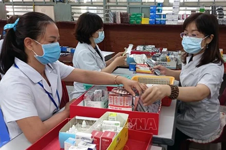 Nhân viên y tế chuẩn bị thuốc để cấp cho bệnh nhân điều trị ngoại trú có tham gia bảo hiểm y tế. (Ảnh minh họa: TTXVN)