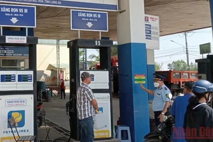 Lực lượng quản lý thị trường tỉnh Long An kiểm tra, giám sát và dán thông tin số điện thoại đường dây nóng để tiếp nhận phản ánh của người dân tại cửa hàng xăng, dầu Quốc Minh, xã Mỹ Hạnh Bắc, huyện Đức Hoà, tỉnh Long An.