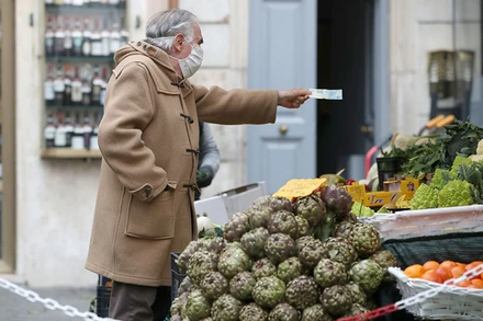 Một người đàn ông đi mua hàng tại Italia. Ảnh: REUTERS