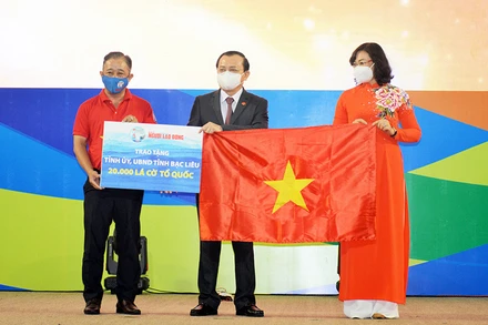 Bà Phan Thị Thắng, Phó Chủ tịch UBND TP Hồ Chí Minh và ông Bùi Thanh Liêm (bìa trái), Phó Tổng Biên tập Báo Người Lao Động, trao cờ Tổ quốc và bảng tượng trưng 20.000 lá cờ cho ông Lê Tấn Cận, Phó Chủ tịch UBND tỉnh Bạc Liêu.