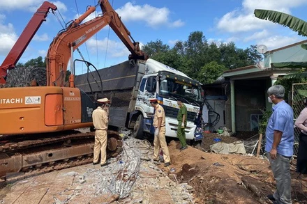 Lực lượng chức năng sử dụng xe chuyên dụng cẩu xe tải, khắc phục hậu quả vụ tai nạn. (Ảnh: TTXVN)