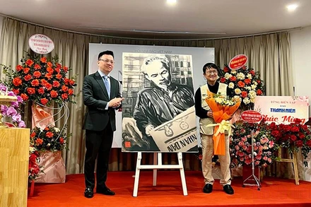 Đồng chí Lê Quốc Minh thay mặt Hội Nhà báo Việt Nam nhận bức vẽ “Bác Hồ đọc Báo Nhân Dân” do tác giả Huỳnh Dũng Nhân trao tặng.
