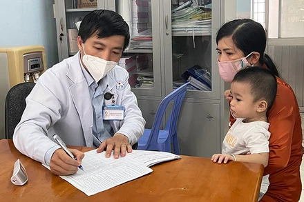 Bác sĩ Phạm Huy Hoàng, Trưởng trạm Y tế phường Trường Thọ, thành phố Thủ Đức, TP Hồ Chí Minh, khám bệnh cho trẻ. (Ảnh: Mạnh Hảo)