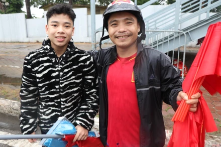Hai cha con anh Nam bán cờ với hy vọng có thêm tiền để mua vé vào sân. (ẢNH: Sơn Bách)
