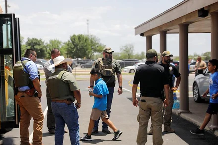 Học sinh lên xe buýt trong sự bảo vệ của lực lượng thực thi pháp luật. (Ảnh: Reuters) 
