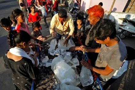 Người dân ở thành phố Ahmedabad, bang Gujarat, Ấn Độ vây quanh 1 xe chở đá để giảm nhiệt giữa nắng nóng gay gắt, ngày 28/4/2022. (Ảnh: Reuters)