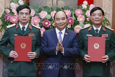 Chủ tịch nước Nguyễn Xuân Phúc, Thống lĩnh các lực lượng vũ trang nhân dân, Chủ tịch Hội đồng Quốc phòng và An ninh trao Quyết định thăng quân hàm từ Trung tướng lên Thượng tướng đối với đồng chí Ngô Minh Tiến và Lương Đình Hồng. (Ảnh: TTXVN)