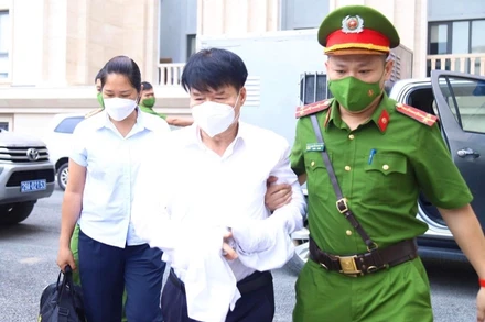 Lực lượng chức năng dẫn giải bị cáo Trương Quốc Cường tới khu vực xét xử. 