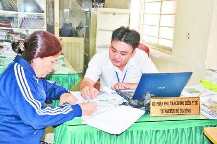 Học tập và làm theo phong cách Hồ Chí Minh, cán bộ phường 9, quận 11 tận tình hướng dẫn người dân thủ tục mua bảo hiểm y tế tự nguyện hộ gia đình.