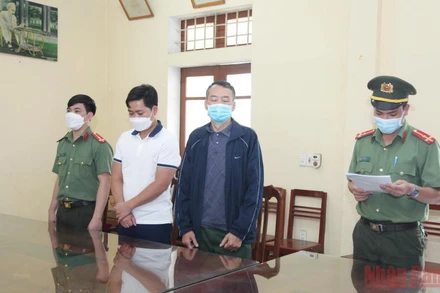 Cơ quan An ninh điều tra đọc lệnh bắt tạm giam đối tượng Khánh và An. (Ảnh: TTXVN)