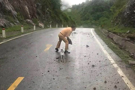 Thiếu tá Đặng Văn Thu bê đá lăn ra khỏi lòng đường để bảo đảm an toàn cho người tham gia giao thông. (Ảnh: Đội Cảnh sát giao thông Na Rì cung cấp)