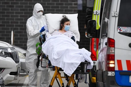 Nhân viên y tế chuyển bệnh nhân Covid-19 lên xe cứu thương tại thành phố Melbourne, Australia. (Ảnh: AFP/TTXVN)