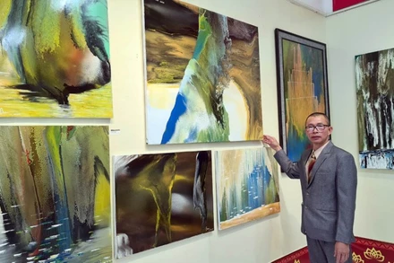 Họa sĩ Võ Trịnh Biện bên những tác phẩm của anh tại triển lãm.