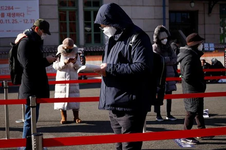 Một người đàn ông Hàn Quốc đọc sách trong khi chờ đến lượt xét nghiệm Covid-19 tại một khu vực xét nghiệm di động đặt trước nhà ga tàu ở Seoul dịp lễ Giáng sinh 2020. Ảnh: Reuters