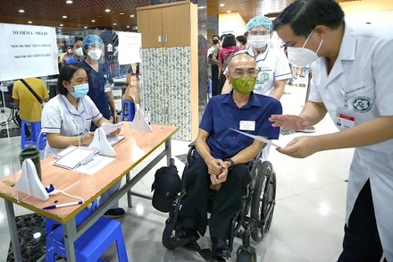 Trước khi tiêm vaccine phòng Covid-19, bác sĩ bệnh viện Bạch Mai đánh giá tình trạng sức khoẻ người khuyết tật theo phiếu sàng lọc.