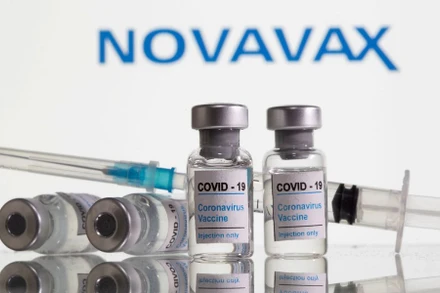 Các lọ dán nhãn vaccine ngừa Covid-19 và ống tiêm được nhìn thấy phía trước logo Novavax. (Ảnh: Reuters).