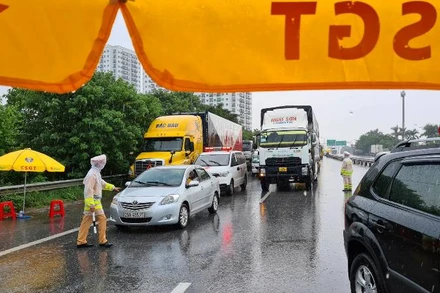 Cảnh sát giao thông làm việc dưới mưa tại Chốt kiểm dịch số 5, khu vực cầu Phù Đổng (Gia Lâm, Hà Nội).