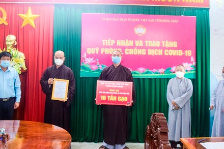 Đại diện Ban Trị sự Phật giáo Việt Nam huyện Châu Thành trao tặng bảng tượng trưng 10 tấn gạo.