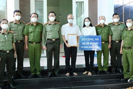 Ðại tá Nguyễn Văn Trãi, Giám đốc Công an tỉnh Tây Ninh (thứ 4, trái sang) trao quyết định của Bộ trưởng Công an, ký thăng cấp từ Đại úy lên Thiếu tá cho gia đình đồng chí Lê Huỳnh Nhật Minh. (Ảnh: Công an Tây Ninh).
