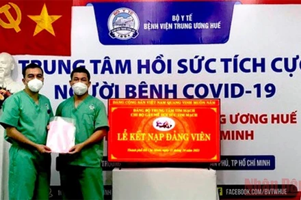 Điều dưỡng Nguyễn Thành Trung (bên trái) vinh dự được đứng vào hàng ngũ của Đảng.