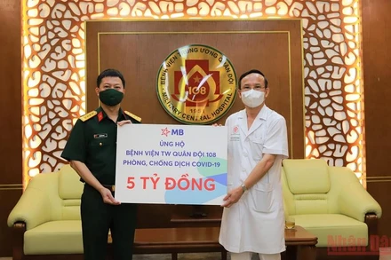 Phó Tổng giám đốc MBbank, Đại tá Trần Minh Đạt (bên trái) trao tặng ủng hộ cho đại diện Bệnh viện Trung ương Quân đội 108. (Ảnh: HỒNG ANH).